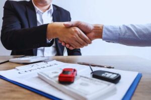 stretta di mano di fronte a un contratto auto