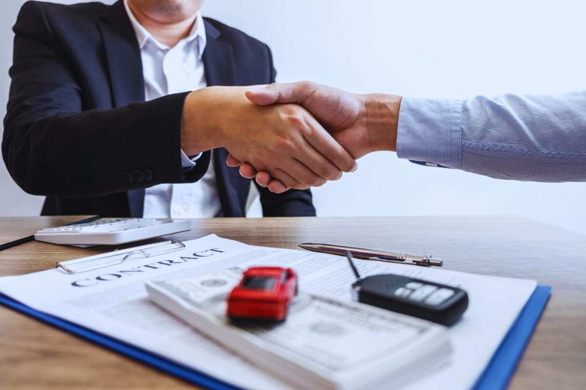 stretta di mano di fronte a un contratto auto