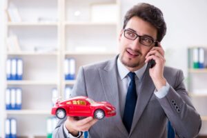 uomo parla al telefono con auto giocattolo in mano