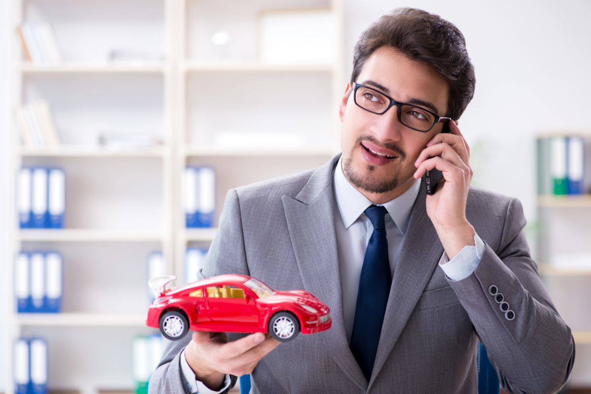 uomo parla al telefono con auto giocattolo in mano