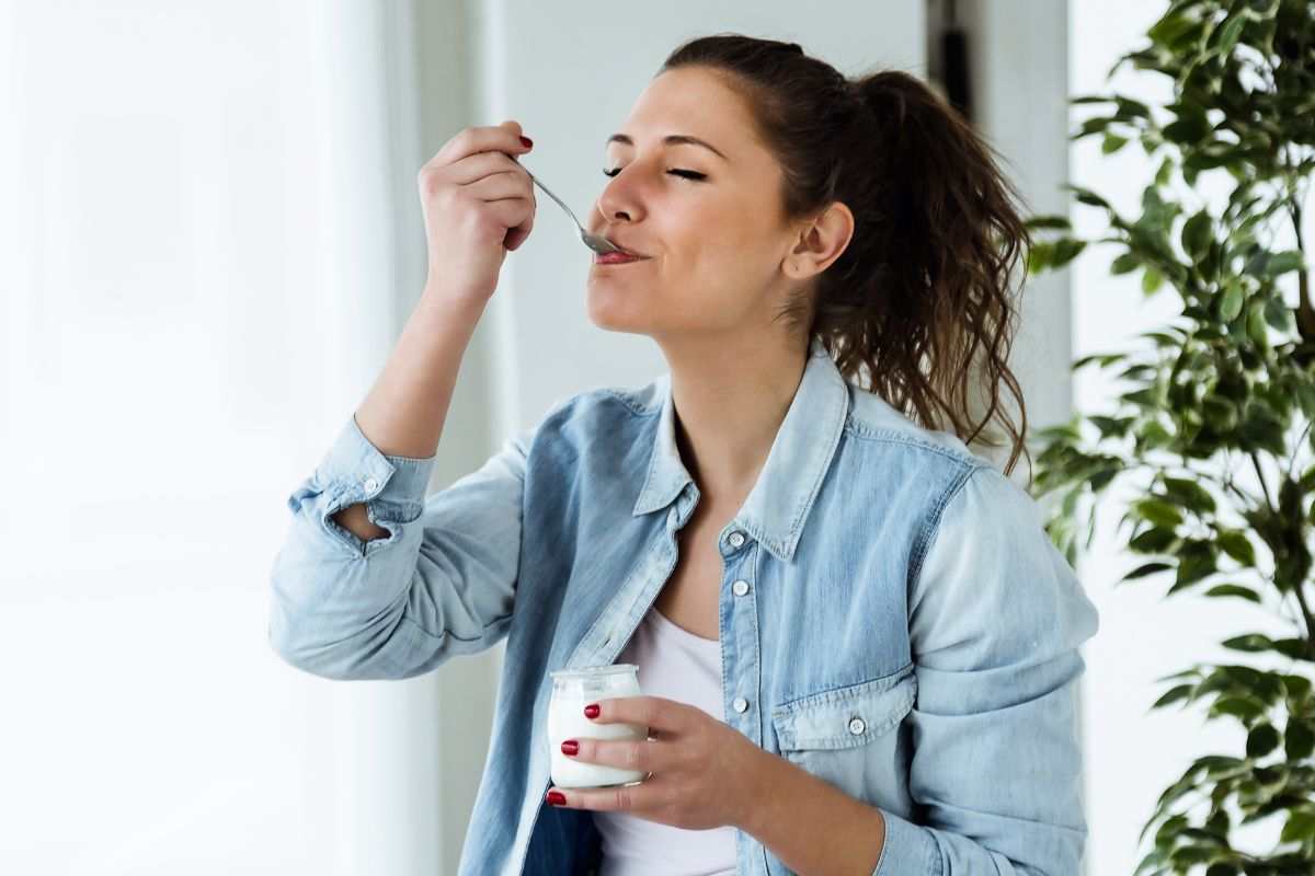 Donna mangia vasetto di yogurt