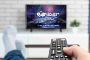 Una persona guarda i canali mediaset col telecomando in mano