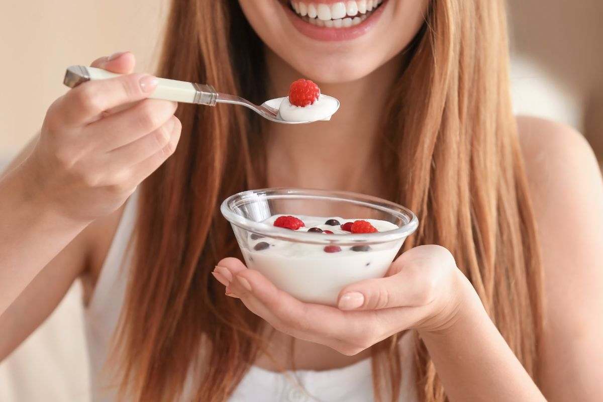 Ragazza consuma yogurt con frutta fresca