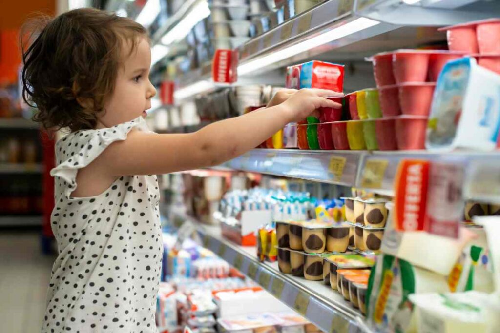 bambina al banco del supermercato sceglie lo yogurt