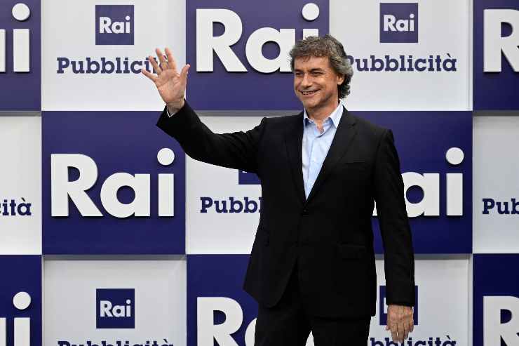 alberto angela saluta davanti al backdrop della ria